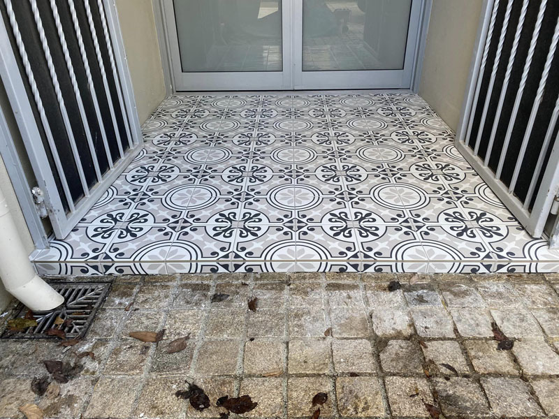 Black and white patterned floor tiles at a back door beside old pavers