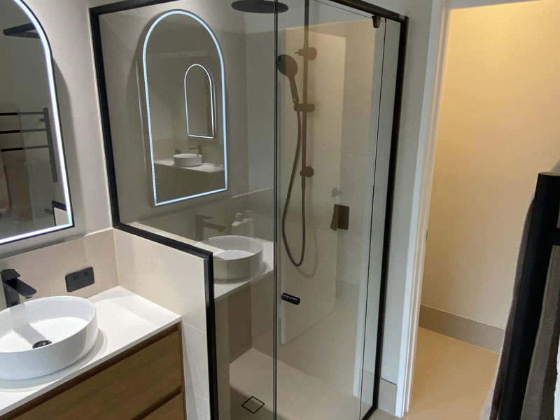 Black-framed shower screen, arched backlit mirror and round basin