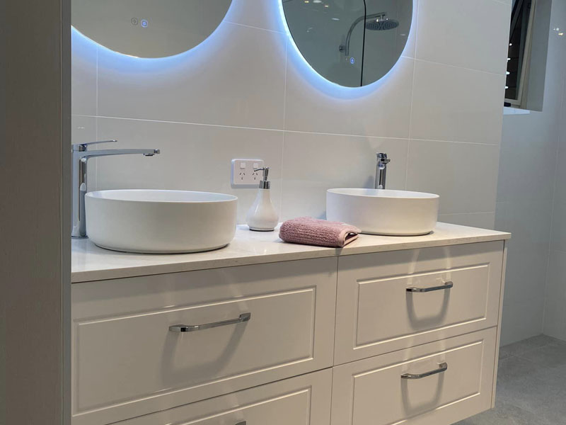 White double vanity with two round basins and backlit round mirrors